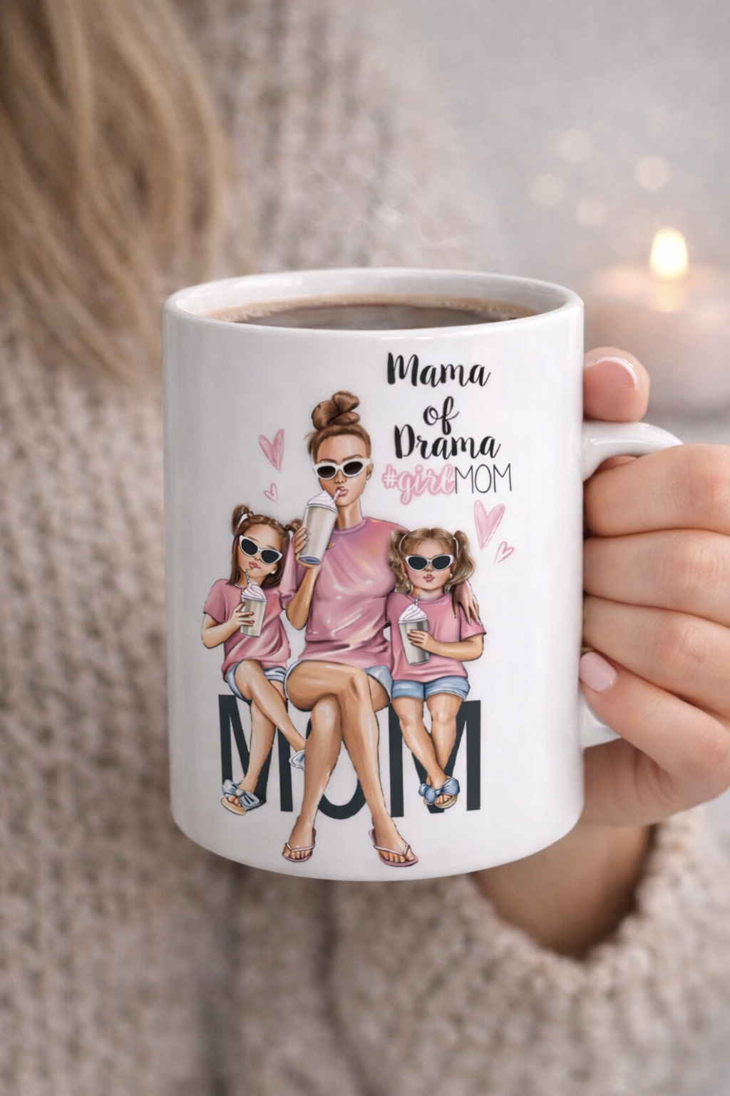 Illustrated mom with two daughters sitting together on a white coffee mug, wearing sunglasses and holding drinks, with “Mama of Drama #girlMOM” text in pink.