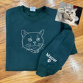 Custom embroidered cat portrait hoodie featuring minimal line art, pet name, and paw print on a cozy sweatshirt.