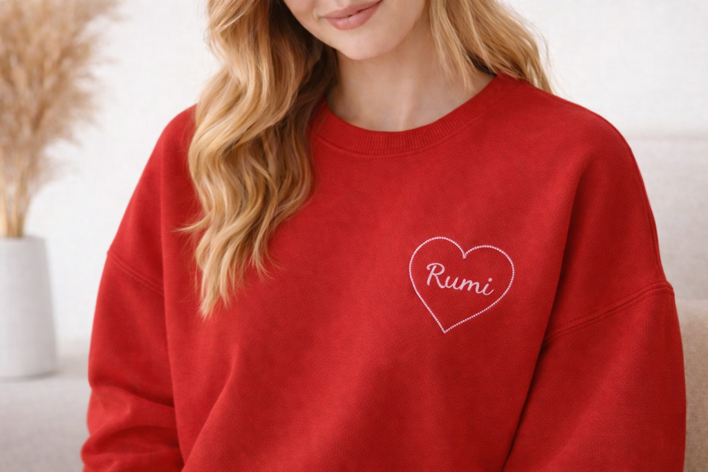 Red personalized sweatshirt with white heart embroidery and the name Rumi worn by a woman

